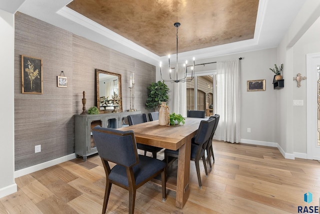 dining area with light hardwood / wood-style floors, a chandelier, and a tray ceiling