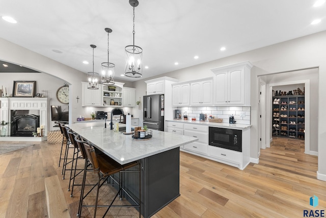 kitchen with pendant lighting, decorative backsplash, white cabinets, black microwave, and high end refrigerator