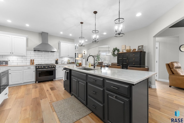 kitchen featuring extractor fan, decorative light fixtures, stainless steel range, white cabinets, and sink