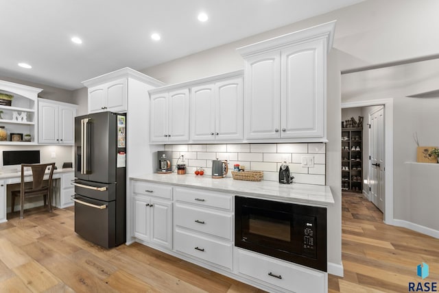 kitchen featuring high end refrigerator, light hardwood / wood-style floors, black microwave, and white cabinetry