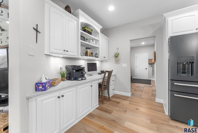 home office with built in desk and light hardwood / wood-style floors