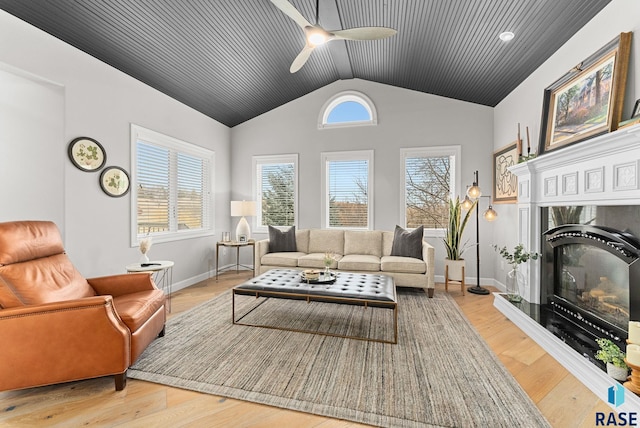 living room with ceiling fan, light hardwood / wood-style flooring, a high end fireplace, and lofted ceiling