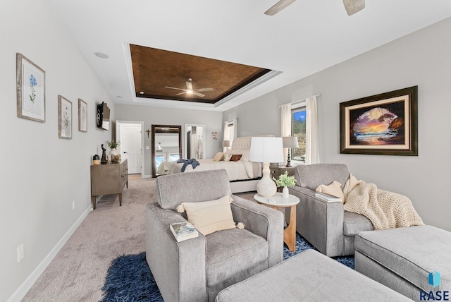 bedroom with ceiling fan, light carpet, and a raised ceiling