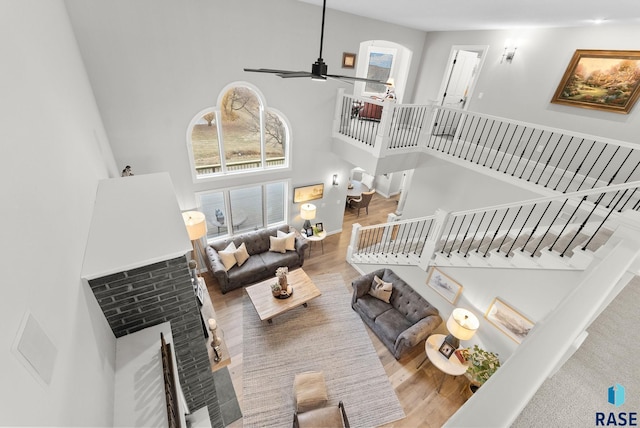 living room featuring ceiling fan, hardwood / wood-style floors, and a high ceiling