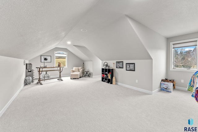 recreation room featuring a textured ceiling, vaulted ceiling, and carpet