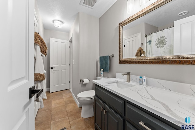 bathroom with toilet, vanity, and a textured ceiling