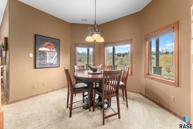 carpeted dining space featuring a chandelier