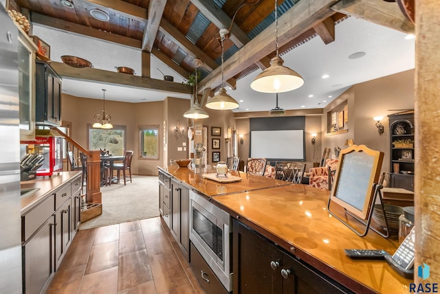 kitchen with carpet flooring, vaulted ceiling with beams, stainless steel microwave, pendant lighting, and wood ceiling