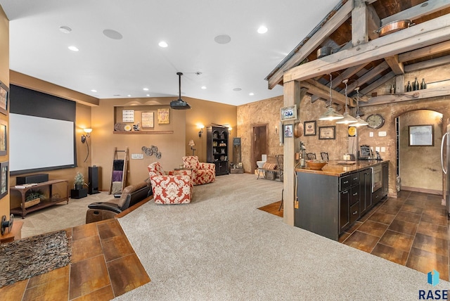 kitchen with vaulted ceiling with beams, dark carpet, dark brown cabinets, dark stone counters, and pendant lighting