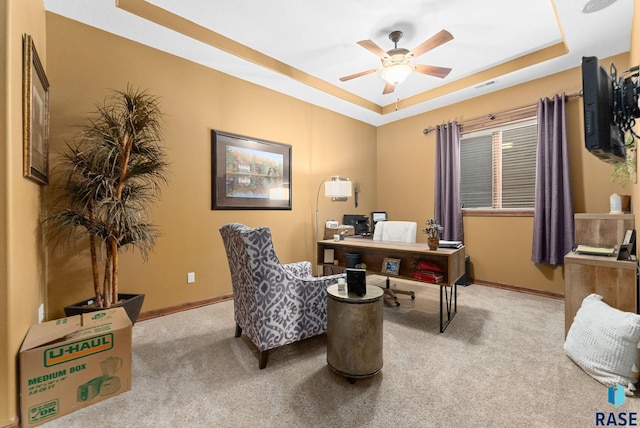 home office featuring ceiling fan, light carpet, and a raised ceiling