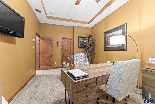 office area featuring ceiling fan, light carpet, and a tray ceiling