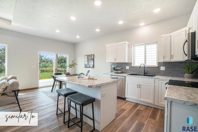 kitchen with a kitchen island, stainless steel appliances, white cabinets, and sink