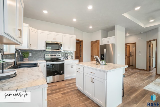 kitchen featuring sink, a center island, white cabinetry, decorative backsplash, and appliances with stainless steel finishes