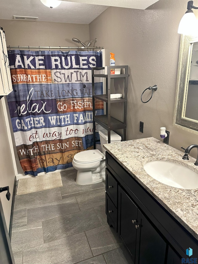 bathroom with toilet, a shower with shower curtain, vanity, and a textured ceiling