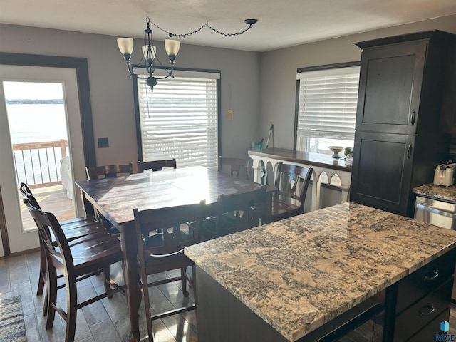 dining area featuring light hardwood / wood-style floors, an inviting chandelier, a healthy amount of sunlight, and a water view