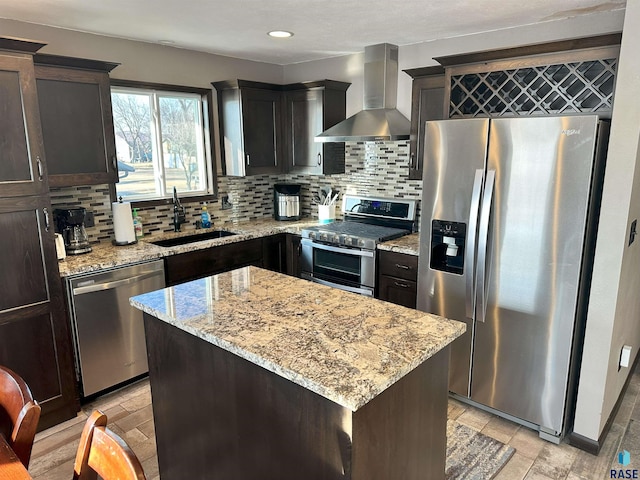 kitchen featuring appliances with stainless steel finishes, a center island, decorative backsplash, sink, and wall chimney range hood