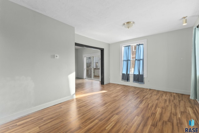 spare room with a textured ceiling and hardwood / wood-style flooring