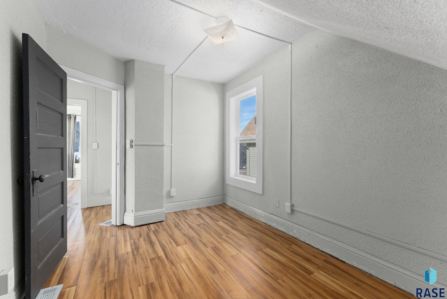 bonus room with a textured ceiling and hardwood / wood-style floors