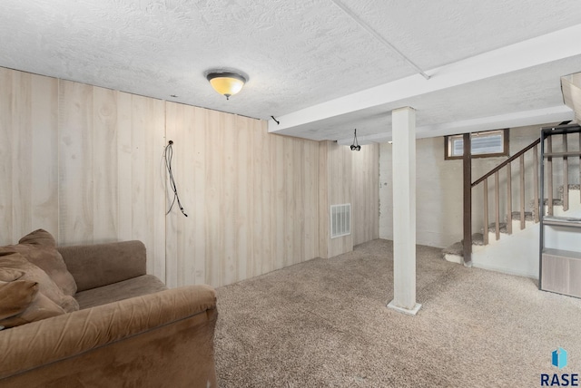 basement with a textured ceiling, wooden walls, and carpet