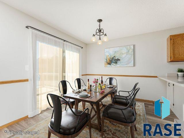 dining room featuring light wood finished floors, baseboards, and a notable chandelier