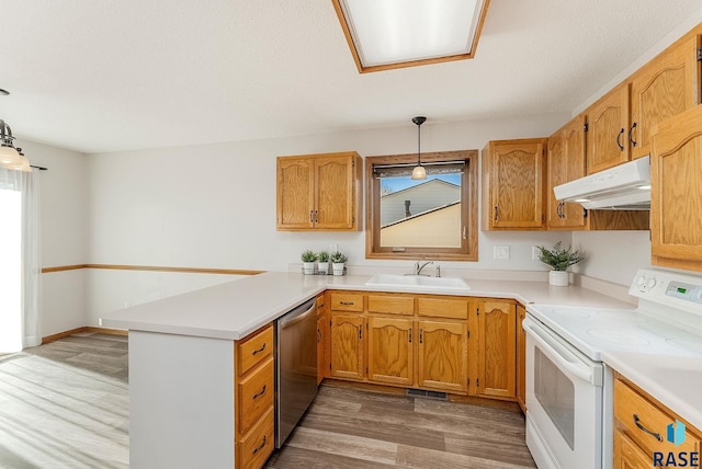 kitchen with electric range, light countertops, under cabinet range hood, pendant lighting, and a sink