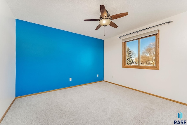 unfurnished room with ceiling fan, a textured ceiling, carpet, and baseboards