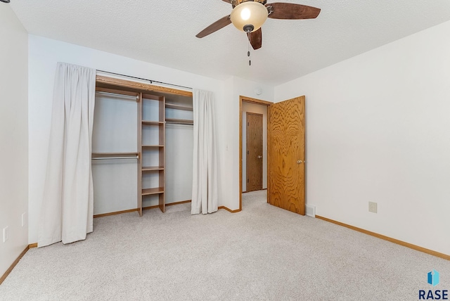 unfurnished bedroom featuring a closet, light colored carpet, a textured ceiling, and baseboards