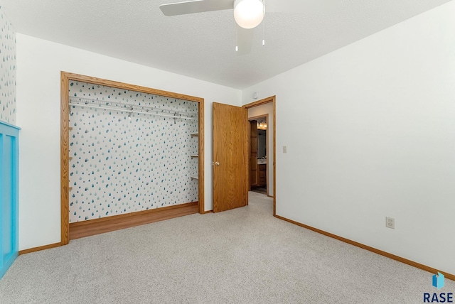 unfurnished room with ceiling fan, a textured ceiling, baseboards, and carpet flooring