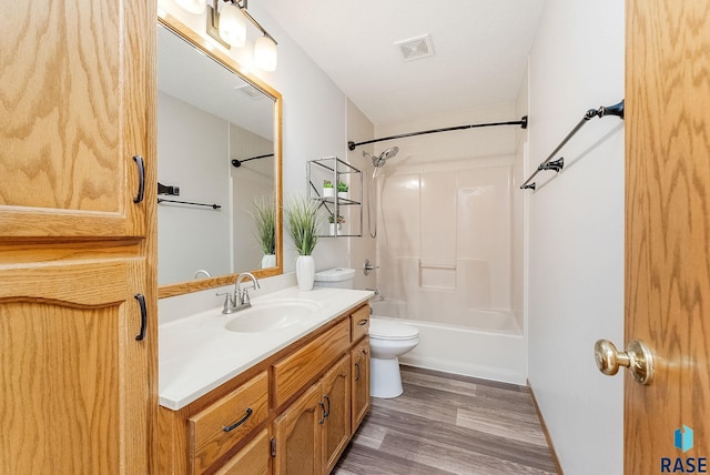 bathroom featuring visible vents, toilet, vanity, shower / tub combination, and wood finished floors