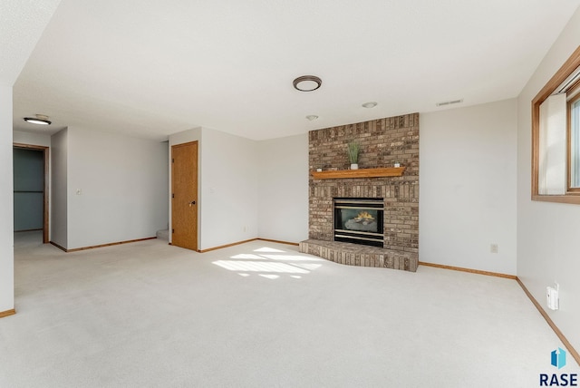 unfurnished living room with baseboards, a fireplace, visible vents, and light colored carpet