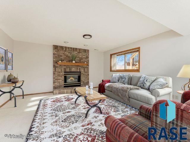 living room featuring carpet, a brick fireplace, and baseboards