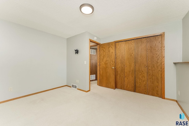 unfurnished bedroom with light carpet, visible vents, and a textured ceiling