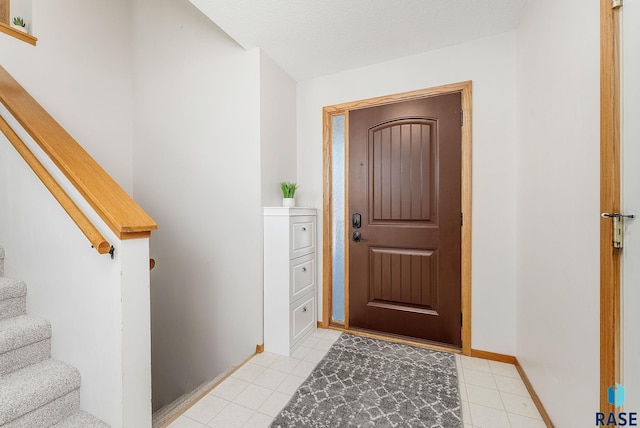 entryway with stairway, baseboards, and a textured ceiling