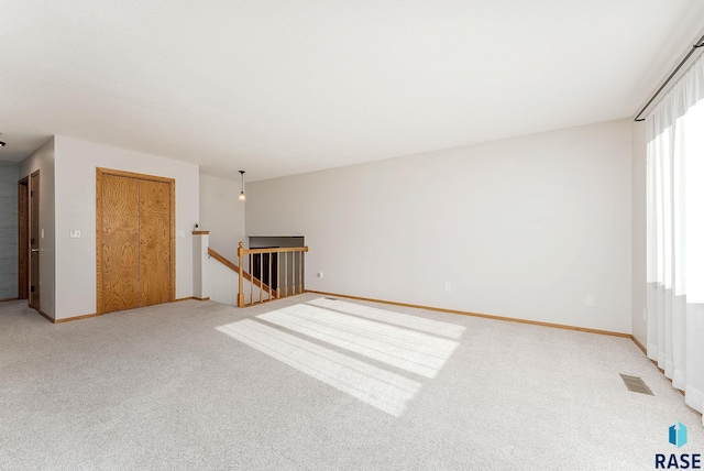 empty room featuring carpet, visible vents, and baseboards