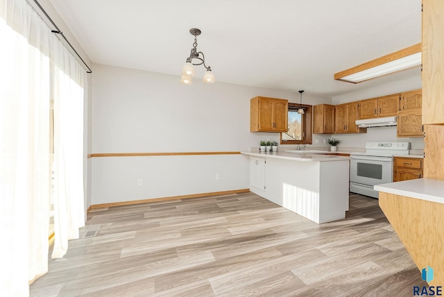 kitchen with under cabinet range hood, electric range, light countertops, a wealth of natural light, and pendant lighting