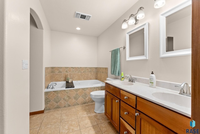 bathroom featuring a relaxing tiled tub, vanity, tile patterned floors, and toilet