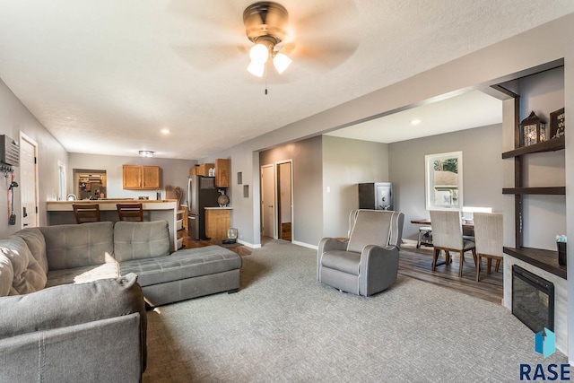 carpeted living room with ceiling fan