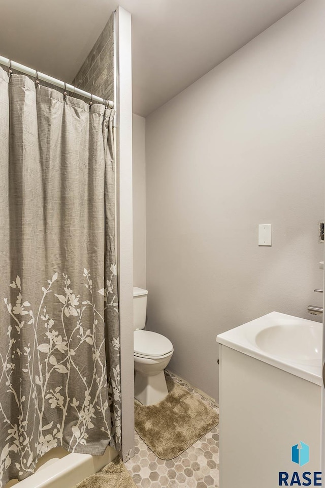 bathroom with toilet, tile patterned flooring, walk in shower, and vanity