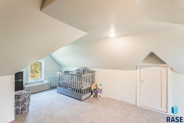 bedroom featuring lofted ceiling, a nursery area, a textured ceiling, and light carpet