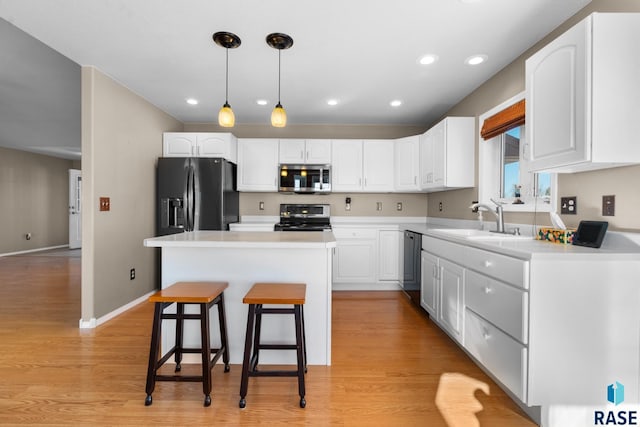 kitchen with sink, white cabinets, a center island, a kitchen breakfast bar, and appliances with stainless steel finishes