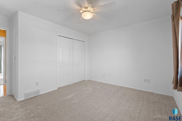 unfurnished bedroom with a closet, light carpet, and ceiling fan