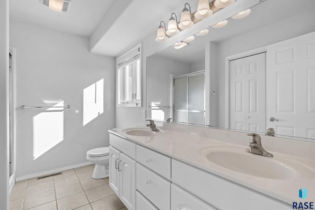 bathroom with toilet, a shower with door, tile patterned floors, and vanity