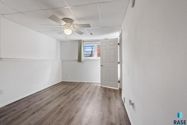 spare room with ceiling fan, a paneled ceiling, and hardwood / wood-style floors