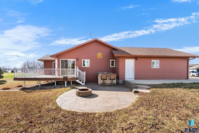 back of house featuring an outdoor fire pit, a yard, a patio, and a wooden deck