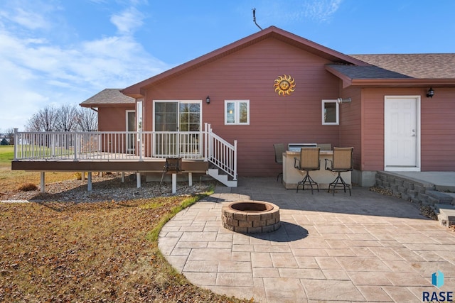 rear view of house with an outdoor bar, a fire pit, a patio area, and a wooden deck