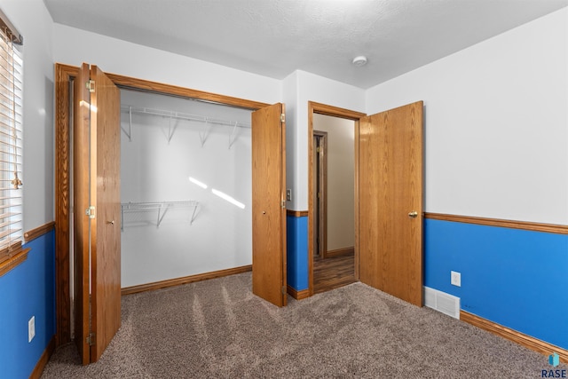 unfurnished bedroom featuring a closet and dark colored carpet