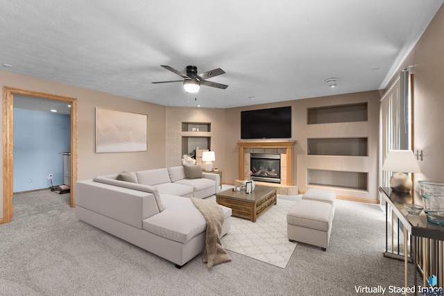 carpeted living room with a fireplace, ceiling fan, and built in features