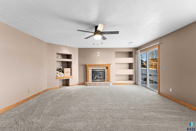 unfurnished living room with built in shelves, a textured ceiling, ceiling fan, and a fireplace