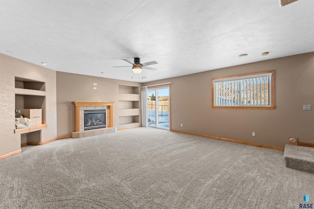 unfurnished living room featuring a textured ceiling, a fireplace, carpet, ceiling fan, and built in shelves