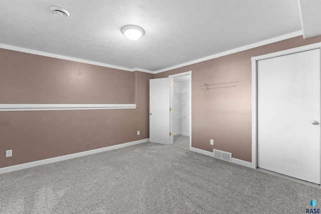 unfurnished bedroom featuring a closet, a textured ceiling, ornamental molding, and carpet